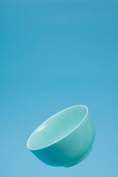 A blue ceramic mattle deep bowl for breakfast flying on blue background. Ideal photo for levitation of food and fruits or nuts.