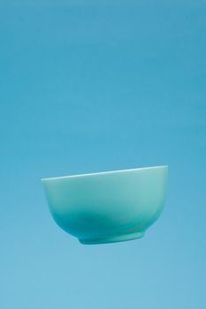 A blue ceramic mattle deep bowl for breakfast flying on blue background. Ideal photo for levitation of food and fruits or nuts.