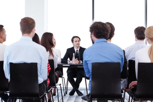 Group of speakers at business meeting at the table with microphones