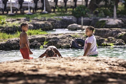 BAYAHIBE, DOMINICAN REPUBLIC 23 DECEMBER 2019: Poor Dominican children play in Bayahibe beach in total happiness and joy