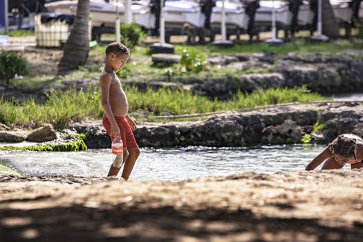 BAYAHIBE, DOMINICAN REPUBLIC 23 DECEMBER 2019: Poor Dominican children play in Bayahibe beach in total happiness and joy