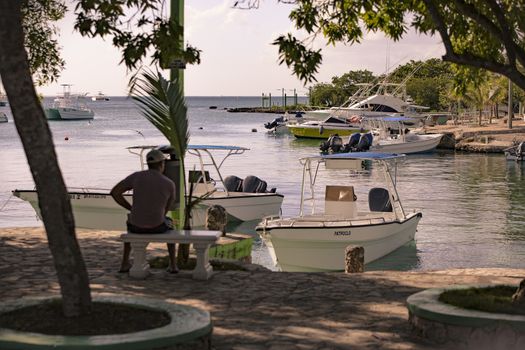 BAYAHIBE, DOMINICAN REPUBLIC 23 DECEMBER 2019: Man sitting on the bench looks at the sea from the port of Bayahibe in Dominican Republic