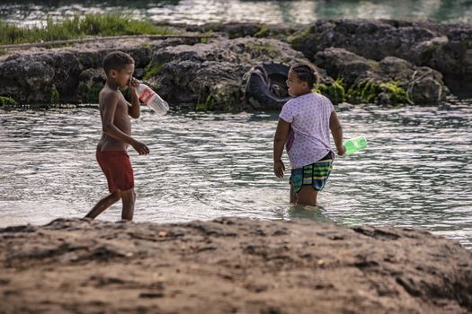 BAYAHIBE, DOMINICAN REPUBLIC 23 DECEMBER 2019: Poor Dominican children play in Bayahibe beach in total happiness and joy