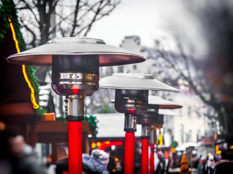 row of gas patio heaters with propane heat lamp on the street in winter day .