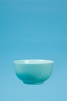 A blue ceramic mattle deep bowl for breakfast flying on blue background. Ideal photo for levitation of food and fruits or nuts.