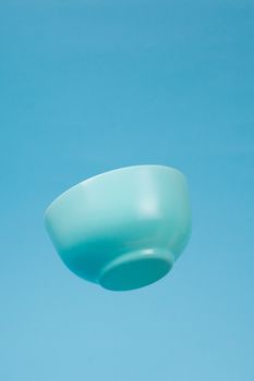 A blue ceramic mattle deep bowl for breakfast flying on blue background. Ideal photo for levitation of food and fruits or nuts.