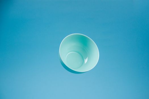 A blue ceramic mattle deep bowl for breakfast flying on blue background. Ideal photo for levitation of food and fruits or nuts.