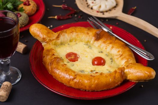 Georgian food on black table. khinkali, phali,  khachapuri with tomatos, adjika and a glass of wine.