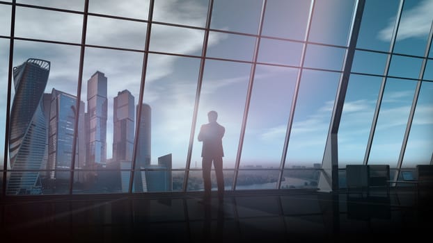 A silhouette of a businessman is looking out of the window of his large office against the backdrop of skyscrapers.