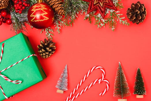 Christmas green gift box and decorations, fir tree branches on red background. Merry Christmas concept. With Copy space for text