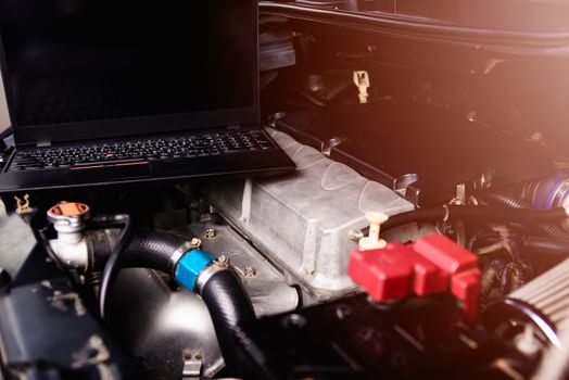 Laptop computer on car mechanic engine for service at workshop