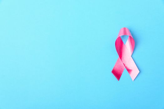 Breast cancer month concept, flat lay top view, pink ribbon on blue background with copy space for your text