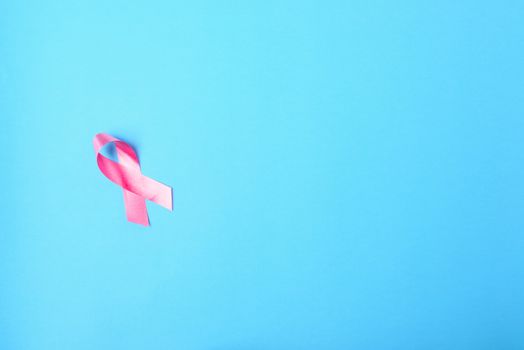 Breast cancer month concept, flat lay top view, pink ribbon on blue background with copy space for your text