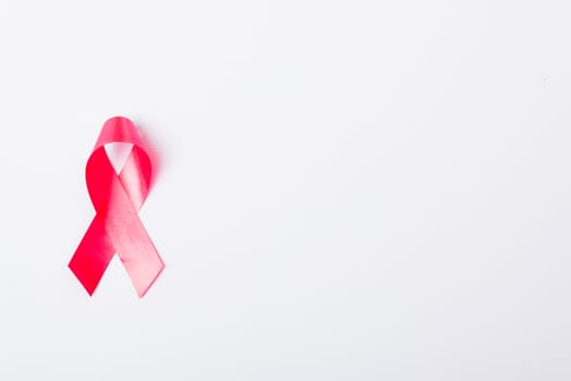 Breast cancer month concept, flat lay top view, pink ribbon on white background with copy space for your text