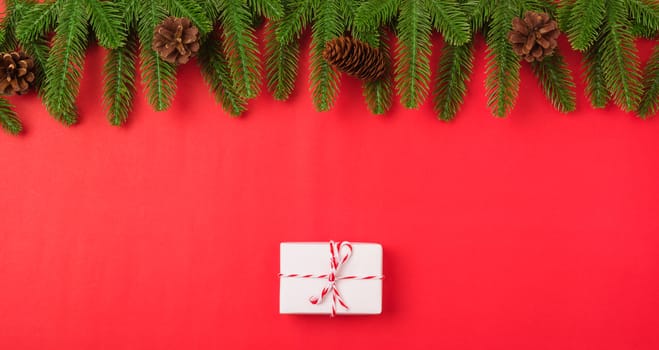 Happy new year or christmas day top view flat lay fir tree branches and gift box, decoration on red background with copy space for your text