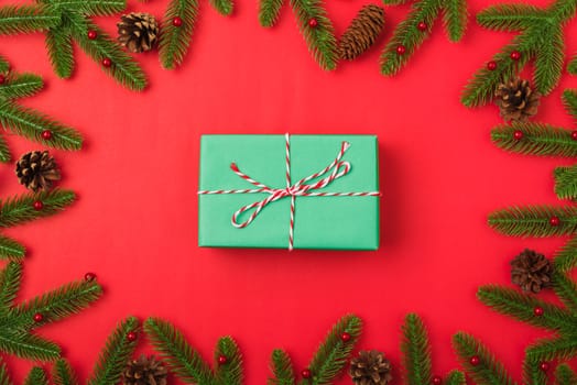 Happy new year or christmas day top view flat lay fir tree branches and gift box, decoration on red background with copy space for your text