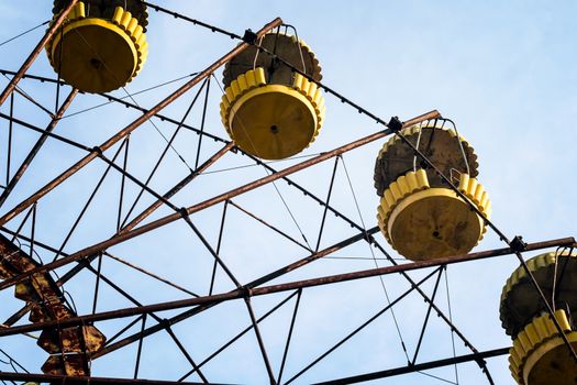 no people carousel cabins in an abandoned amusement park on a background of blue sky and clouds in Chernobyl Ukraine