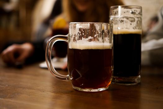 Two glasses of dark beer on a wooden table