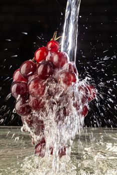 Bunch of grapes and stream of water on a studio background