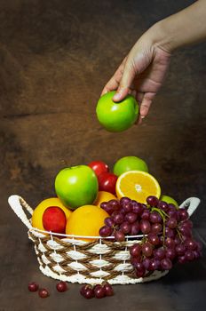 fresh vegetables and fruits in wicker basket over wooden background