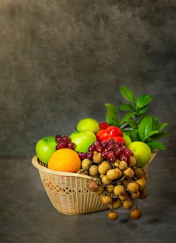 fresh vegetables and fruits in wicker basket over wooden background