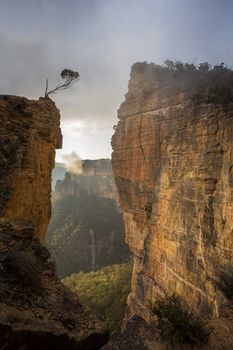 Views through sheer sandstone cliff faces as fog and cloud lift out of the valley. Blackheath Australia