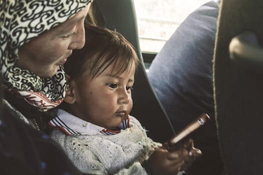 Close up portrait of a Tibetan kid sitting on her mother’s lap on the Parents Day Holiday in morning time of a day. Tibet Autonomous region, India South Asia Pac May 2019