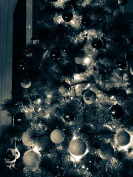 Monochrome photo of a Christmas tree with white and black gifts in the night. Magic time.