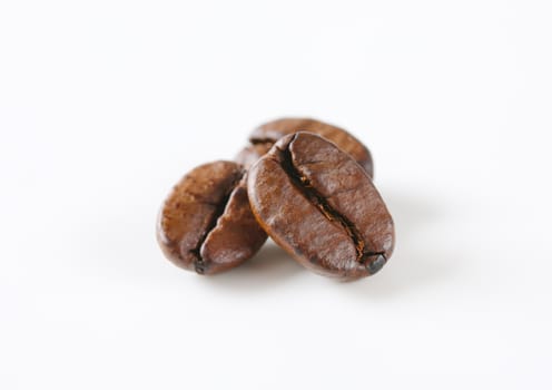 Three roasted coffee beans on white background