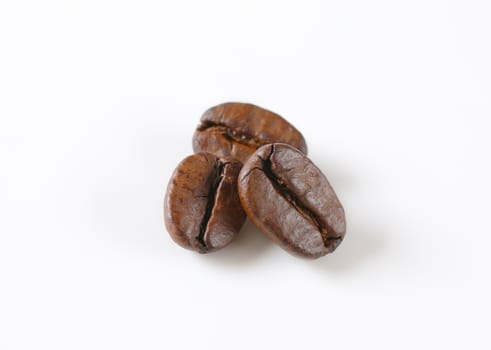 Three roasted coffee beans on white background