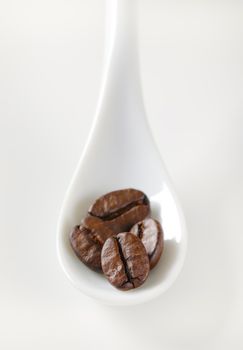 roasted coffee beans on white porcelain spoon