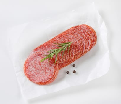 Sliced salami sausage on white wax paper