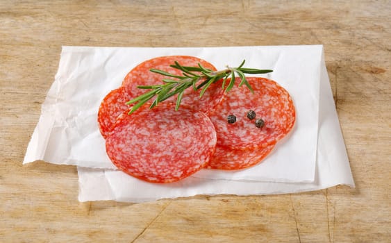 Sliced salami sausage on white wax paper