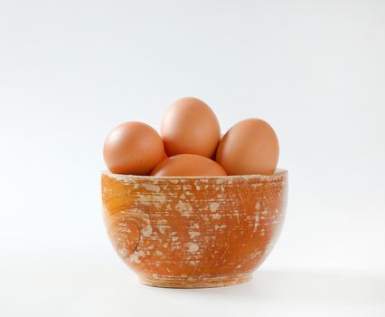 Fresh brown eggs in wooden bowl