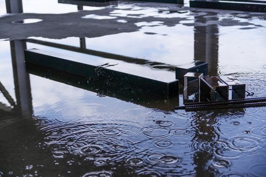 Rain drops and water on concrete with sky reflection in water