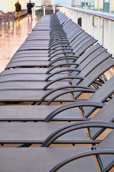 Lounge Chairs LIned up on Ships Deck with Walkers in Background