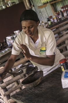 MONTANA REDONDA, DOMINICAN REPUBLIC 27 DECEMBER 2019: Dominican woman grinds coffee with traditional methods