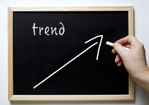 a blackboard with writing trend and an arrow indicating the rise