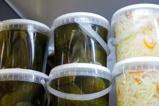 Canned, marinated fermented and pickled vegetables in plastic jars. Sauerkraut, pickles, pickled ginger in the grocery store.