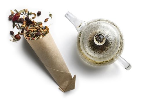 Green tea with natural aromatic additives and a teapot. Top view on white background.