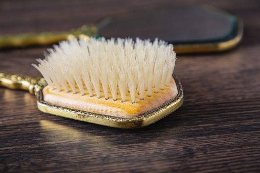 close up of an antique hair brush and hand mirror on a dark oak wood floor