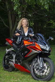 young blond motocyclist, sitting on a sport motocycle, making a face