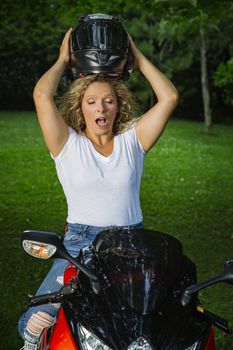 Woman trying to fit a sport motocycle helmet on top of her head