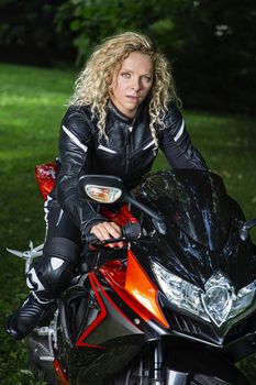 twenty something blond woman, sitting on a sport motocycle, wearting leather pants and jacket