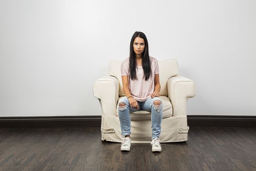 Twenty something woman, wearing ripped jeans, sitting on a white couch