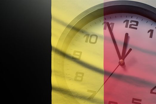 Belgium flag with dial of a clock counting down to twelve noon or midnight in a concept of crisis, deadlines or new year,