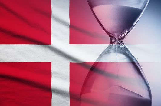 Flag of Denmark with superimposed hourglass with running sand conceptual of deadlines, countdown, passing time, urgency, crisis and time management