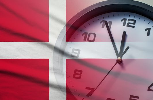 Denmark flag with dial of a clock counting down to twelve noon or midnight in a concept of crisis, deadlines or new year,