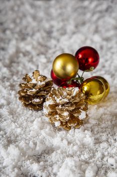 two golden pine cone and small christmas decoration in the snow
