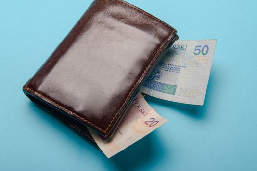 brown mans leather wallet with money bills on a blue background